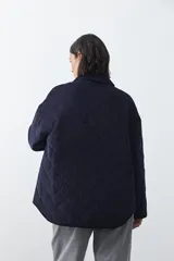 Campera capitoneada de algodón con diseño matelaseado, cuello camisero y cierre frontal con botones a presión. Presenta un corte relajado y bolsillos frontales.