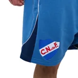 Short deportivo Umbro del Club Nacional de Football, color azul melange, con cordón ajustable en la cintura, bolsillos laterales, el escudo del club bordado en la pierna derecha y el logo de la marca en la izquierda.