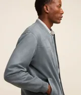 Chaqueta bomber azul marino lisa, con cierre frontal, cuello redondo y bolsillos laterales.