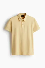 Remera polo de manga corta en color amarillo, confeccionada en punto de algodón liviano. Presenta cuello clásico, tapeta con dos botones, bajo recto y un corte entallado al cuerpo.