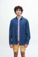 Camisa de denim celeste, manga larga, confeccionada en tela 100% algodón. Tiene un bolsillo en el pecho y botones personalizados.