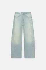 Jeans baggy de tiro medio, pierna ancha y diseño de cinco bolsillos, confeccionados en denim celeste con aplicaciones de brillos en los laterales.