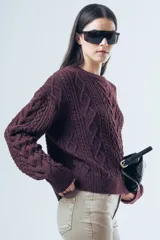 Sweater de punto color bordó con diseño de trenzas y relieves. Presenta cuello redondo, mangas largas y terminaciones acanaladas en puños y ruedo.