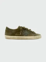 Zapatillas Golden Goose modelo Super Star, color verde oliva con efecto desgastado. Presentan una estrella lateral en tono más oscuro, cordones al tono y suela con acabado envejecido.