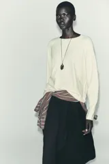 Jersey oversize de punto color crema, con cuello redondo y manga larga. Presenta costuras marcadas en los hombros y los laterales.