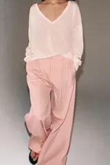 Pantalón de tiro medio con corte wide leg, confeccionado en algodón. Presenta cintura con trabillas, bolsillos laterales ocultos y detalle de pliegues en el delantero. Cierre frontal con cremallera, botón y ganchos metálicos.