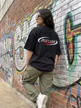 Remera negra de algodón con corte oversize y estampado frontal con la palabra "Blessed" en blanco y "by God" en rojo.
