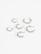 Set de tres pares de aros tipo argolla, de diseño bold y acabado plateado brillante.