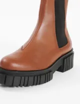 Botas Chelsea de cuero color marrón con elástico lateral negro y suela track negra.