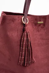 Bolso tipo tote de gran tamaño en color bordó, confeccionado en material con textura similar a la gamuza. Cuenta con doble asa larga para llevar al hombro y una pequeña placa metálica decorativa en el frente.