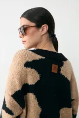 Sweater de punto con diseño animal print en bloques de color negro y beige, con cuello en V y terminaciones acanaladas en puños y ruedo.
