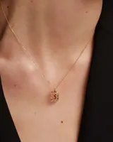 Collar de plata dorada con cadena de eslabones y un dije colgante en forma de letra 'S' dentro de un aro ovalado decorado con cristales multicolor.