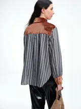 Camisa de corte relajado con estampado de rayas verticales, destacada por detalles en terciopelo en el cuello, puños y canesú. Presenta cierre frontal con botones y mangas largas.