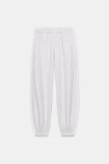 Pantalón jogger de felpa color gris claro melange, de tiro medio con cintura elástica. Presenta detalles de aplicaciones tejidas a contraste en los laterales y terminaciones con puños abullonados.