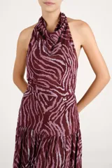 Vestido largo bordó con estampado animal print abstracto en tonos rosados, con cuello halter y falda escalonada con volados.
