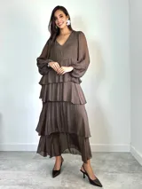 Vestido largo de seda italiana color chocolate, con escote en V, mangas largas abullonadas y diseño de falda con volados escalonados.