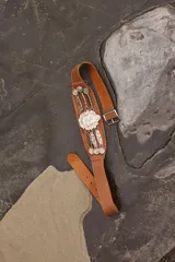 Cinturón tipo rastra color beige con apliques metálicos plateados y escudo de Uruguay en el centro.