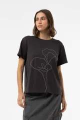 Remera de algodón con calce relajado, color negro lavado, cuello redondo y mangas cortas. Presenta una estampa floral bordada en líneas blancas en el frente.