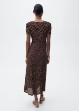 Vestido midi de corte recto con estampado de lunares, cuello en pico y mangas cortas. Presenta cierre de cremallera lateral y abertura en el bajo.