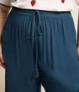 Pantalón pantacourt plus size de viscosa color azul, con cintura elástica y cordón de ajuste con borlas. Presenta un diseño fluido y dobladillo asimétrico.