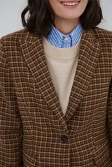Blazer de paño con estampado de cuadros en tonos marrones, con solapas clásicas, hombreras, cierre frontal con un botón y botones decorativos en los puños.