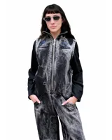 Mono de denim con efecto de lavado ácido en tonos grisáceos y negros. Presenta cierre frontal completo, cuello alto, bolsillos laterales y bordados decorativos en color azul en la parte superior del pecho. De diseño utilitario y corte holgado.