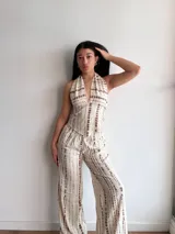 Pantalón de corte holgado y tiro alto, con diseño estampado de rayas verticales discontinuas en tonos beige y marrón. Presenta cintura elástica y caída fluida.