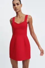 Vestido corto de color rojo con escote corazón estilo corsetero, tirantes anchos y falda con corte evasé. Cuenta con cierre de cremallera oculto en la espalda.