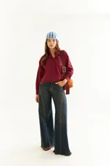 Camisa de corte boxy y calce holgado, color bordó, con cuello clásico, cierre frontal de botones y detalle de tablas con recortes diagonales en el pecho.