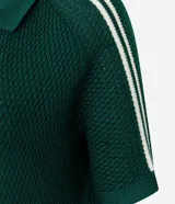 Blusa femenina de punto color verde oscuro, con cuello polo y abertura delantera sin botones. Presenta una trama ahuecada con textura uniforme y mangas cortas con detalle de rayas blancas en los hombros. El modelo es recto y de largo regular.