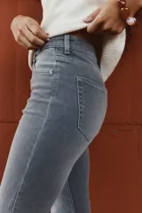 Jeans de tiro alto, color gris oscuro lavado, con corte ajustado en la parte superior y pierna acampanada (flare) desde la rodilla hasta el bajo. Presenta cinco bolsillos y cierre frontal con botón.