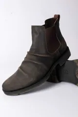 Bota tipo Chelsea de cuero color marrón oscuro con efecto desgastado, paneles laterales elásticos y suela de goma antideslizante.