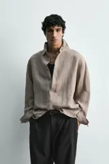 Camisa de corte regular confeccionada en lino, con cuello solapa y cierre frontal de botonadura oculta. Presenta mangas largas con puños abotonados.
