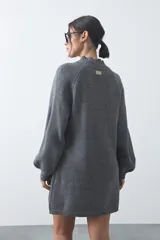 Vestido corto de punto en color beige, con cuello alto acanalado, mangas largas con puños ajustados y diseño holgado.