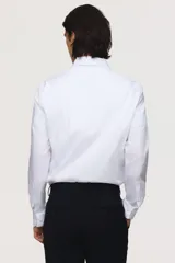 Camisa blanca de manga larga, corte slim fit, confeccionada en tejido elástico de mezcla de algodón. Presenta cuello italiano, tapeta lisa con botones y puños ajustables con botón.