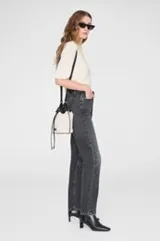 Bolso tipo balde con cuerpo de lona color beige y detalles en cuero negro. Cuenta con cierre de cordón ajustable, herrajes dorados y correa larga regulable para llevar cruzado o al hombro.