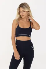 Top deportivo negro con breteles finos regulables y contorno inferior blanco.