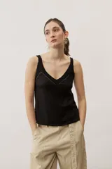 Musculosa de lino color negro con tirantes anchos de encaje y detalle de aplique metálico con la marca en la parte posterior.