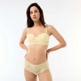 Shorty de encaje floral transparente en color amarillo pastel, con bordes festoneados y pequeño lazo decorativo en el centro de la cintura.