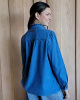 Camisa de jean azul con cuello alto con volados y volados en el frente.