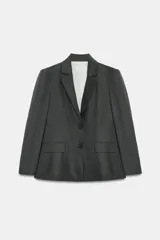 Blazer entallada gris confeccionada en mezcla de lino, con cuello solapa, manga larga con hombreras, falsos bolsillos con solapa en el delantero y cierre frontal con botones.