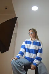 Sweater de punto a rayas horizontales azules y blancas, con cuello polo y cierre parcial con cremallera.