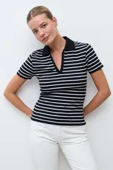Remera de tejido canalé a rayas horizontales blancas y negras, con cuello polo y escote en V sin botones, de manga corta y corte ajustado.