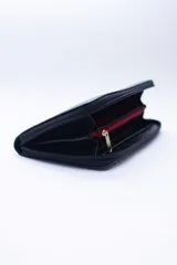 Billetera rectangular con cierre perimetral, confeccionada en cuero con textura de reptil. Cuenta con múltiples compartimentos internos para tarjetas, documentos y billetes, además de un bolsillo interior con cierre para monedas.