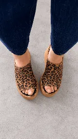 Zuecos con plataforma corrida y capellada amplia de cuero con estampado animal print tipo leopardo.