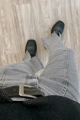 Pantalón jean gris de tiro medio alto, corte wide leg con tajo frontal.