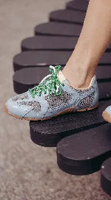 Zapatillas urbanas de cuero celeste y mesh gris, con suela de goma y doble juego de cordones intercambiables en color verde y blanco.