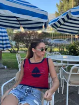 Top tejido a mano en hilo de algodón color rojo oscuro, con bordado artesanal de barco en el frente y ribete azul marino.