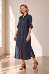 Vestido chemise largo color azul marino con botones frontales contrastantes, mangas tres cuartos con detalles bordados y aberturas laterales en el bajo.