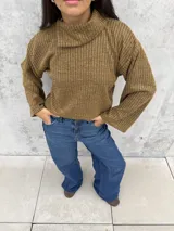 Polera de tejido de punto acanalado en color ocre, con cuello alto y diseño de mangas amplias. Presenta un corte recto y holgado con un detalle de cuello abierto lateral.